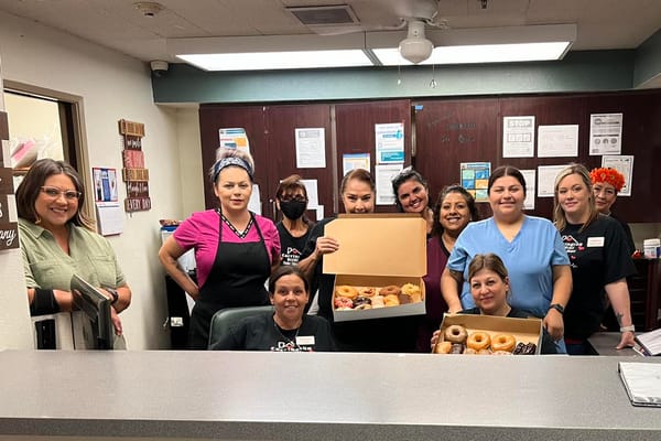 Staff members at the reception area with a box of donuts