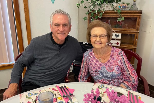 Resident and staff member smiling together at a table