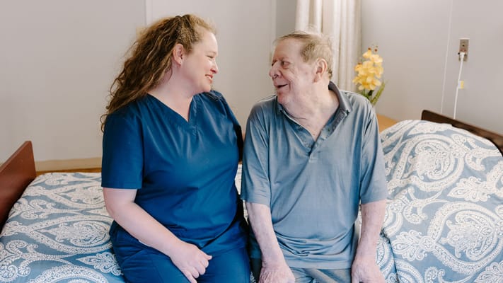 Staff member and resident smiling together in a cozy room