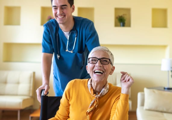 A caregiver and a resident smiling in a bright common area