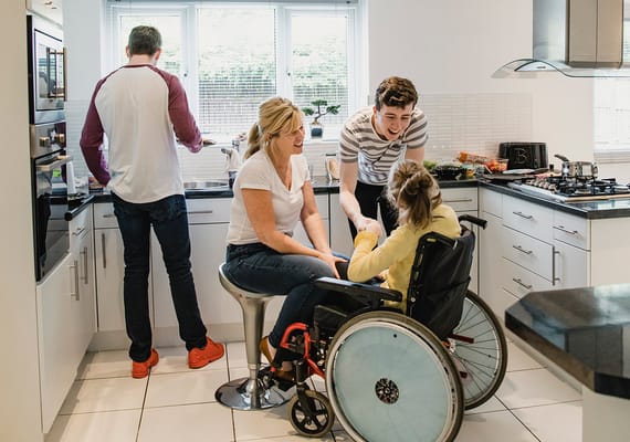 A family interacting with a resident in a kitchen