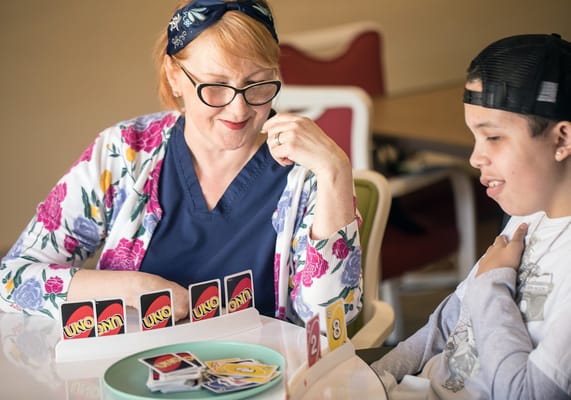 Resident playing UNO with staff member in an activity room
