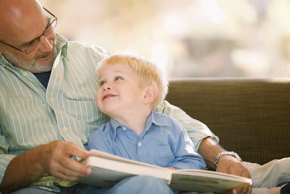 Grandfather reading with his grandson in a cozy interior