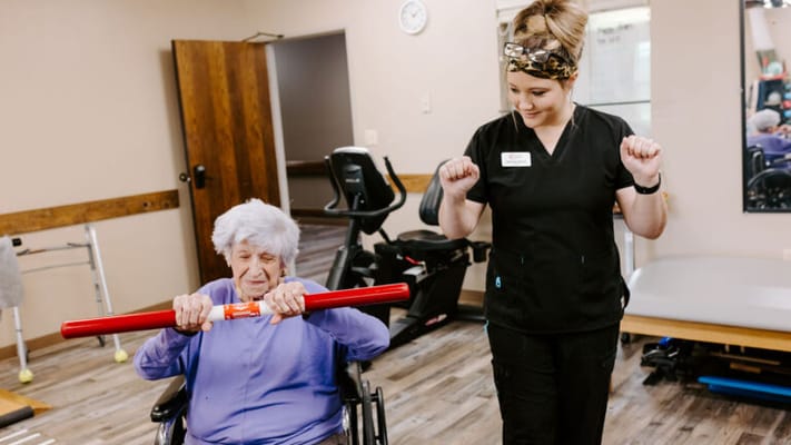Staff assisting a resident with rehabilitation exercises