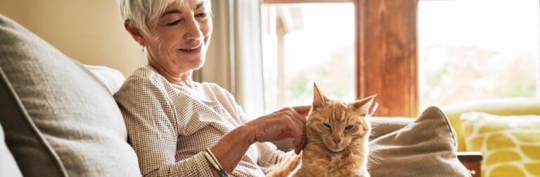 Senior woman petting a cat in a cozy living room