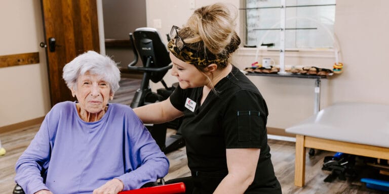 A caregiver assisting a resident in a therapy room.