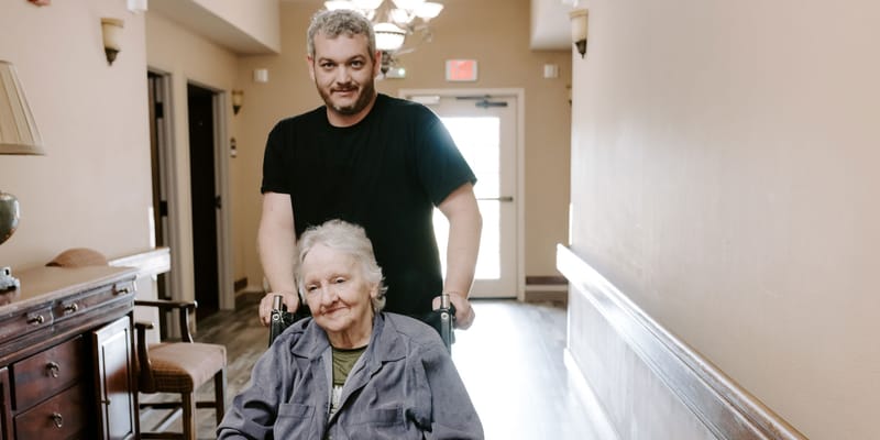 A caregiver assisting a resident in a hallway