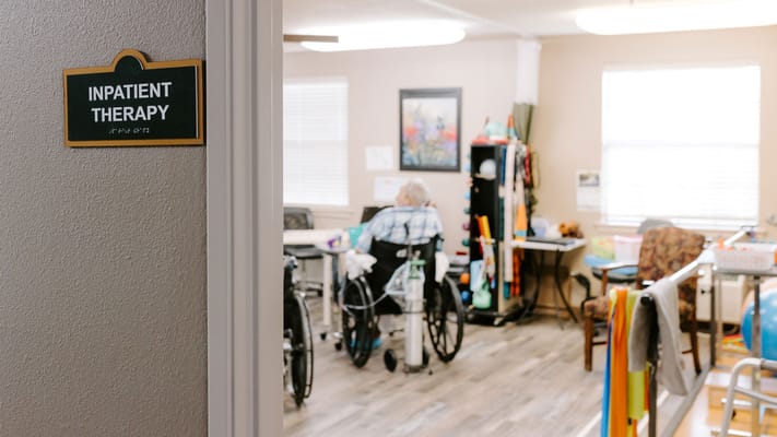 A sign indicating inpatient therapy room with resident in wheel chair