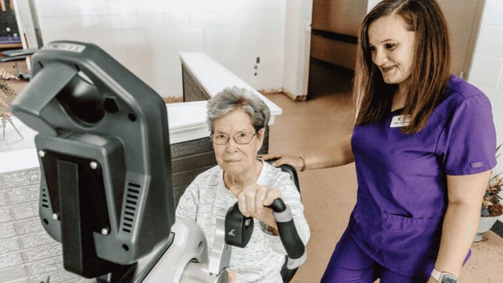 Staff assisting a resident with exercise equipment