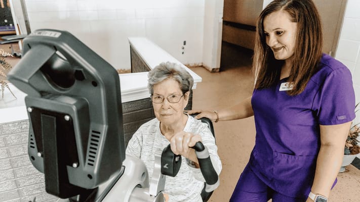 Staff assisting a resident with exercise equipment