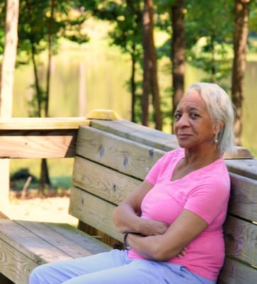 Senior resident relaxing on a bench near a pond