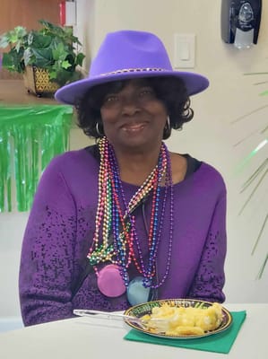 Resident celebrating with beads and food in the dining area