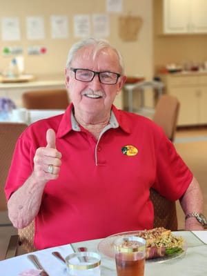 Resident enjoying a meal with a thumbs-up