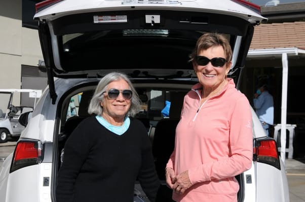 Two women smiling near a vehicle