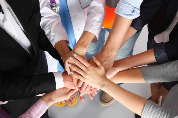 Hands of diverse individuals stacked together in support