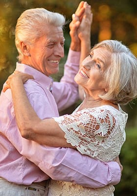 Elderly couple dancing joyfully outdoors