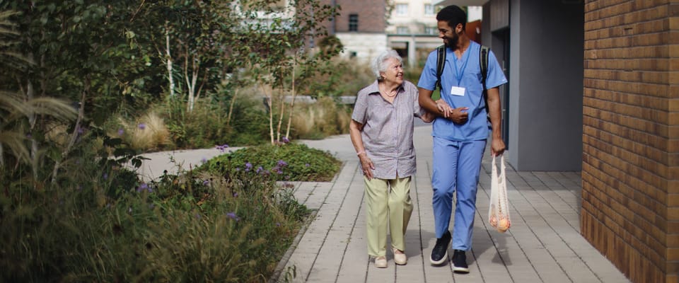 Caregiver and resident walking in a garden path