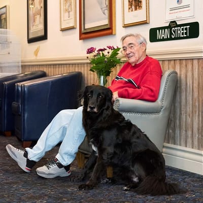 Resident seated with a dog in a cozy lounge