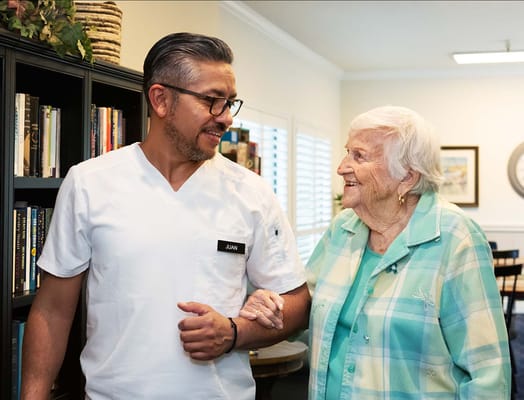 Staff member assisting a resident in a bright interior space