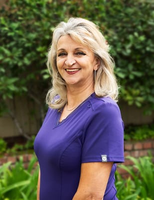 Staff member smiling in a garden setting