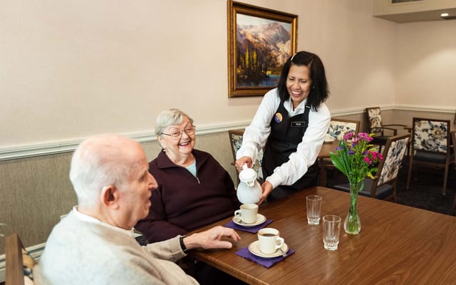 Staff serving coffee to residents in a dining area
