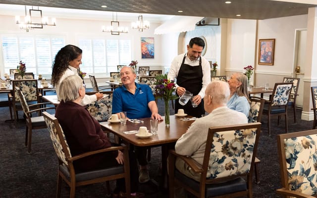 Residents enjoying a meal in the dining room with staff assistance