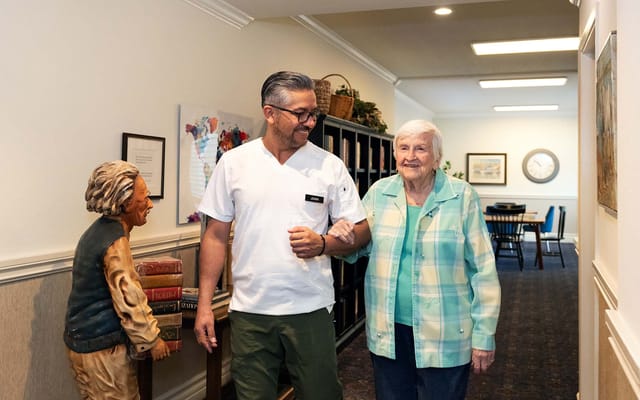 A staff member and resident walking down a hallway