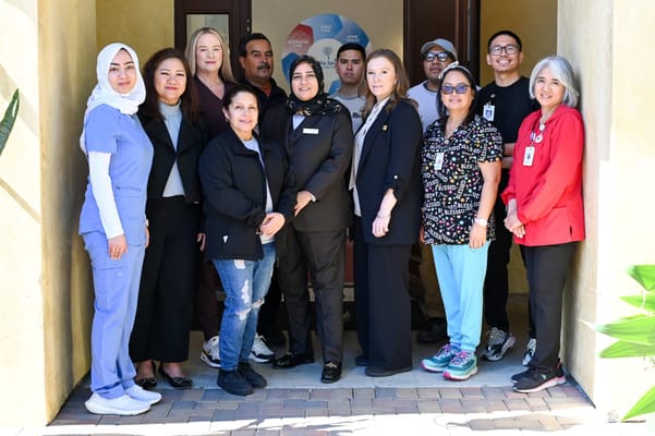 Staff members posing in front of the facility entrance
