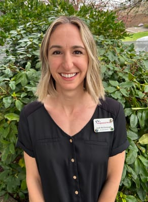 Staff member posing in front of greenery