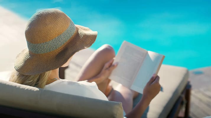 A person reading a book by the poolside