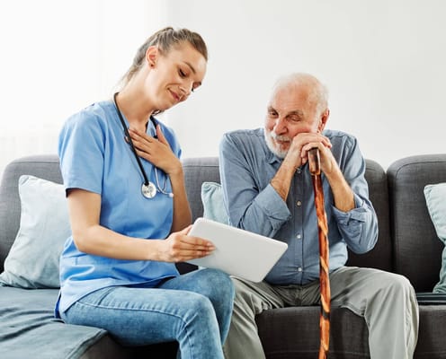 Nurse assisting a resident with a tablet in a living space