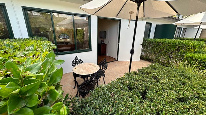 Outdoor seating area with table and chairs surrounded by greenery