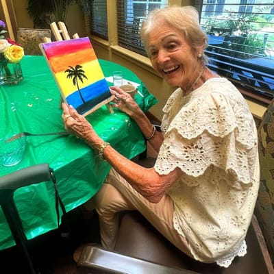 Resident painting at a table during an activity