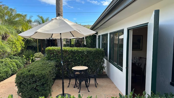 Outdoor seating area with patio umbrella and greenery