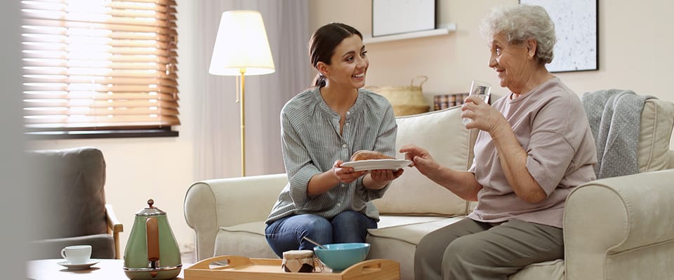 A caregiver serving food to a smiling senior resident