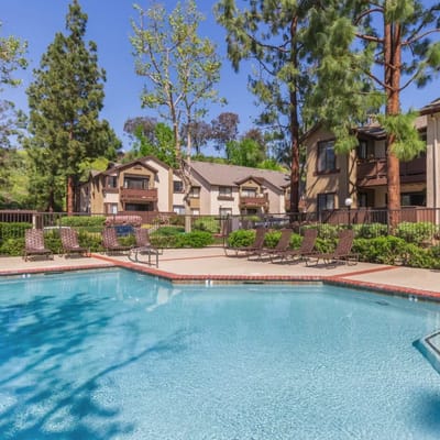 Outdoor view of a pool surrounded by seating and trees