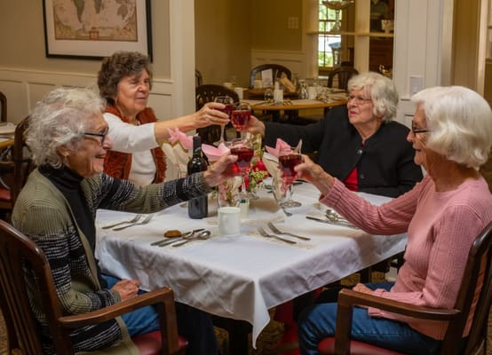Residents toasting with drinks in a dining room
