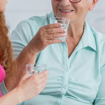 Staff member and resident sharing drinks in a cozy setting