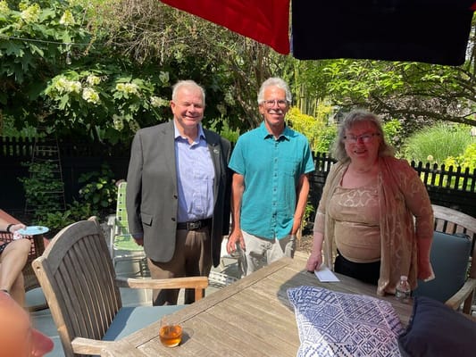 Three people smiling in an outdoor garden setting