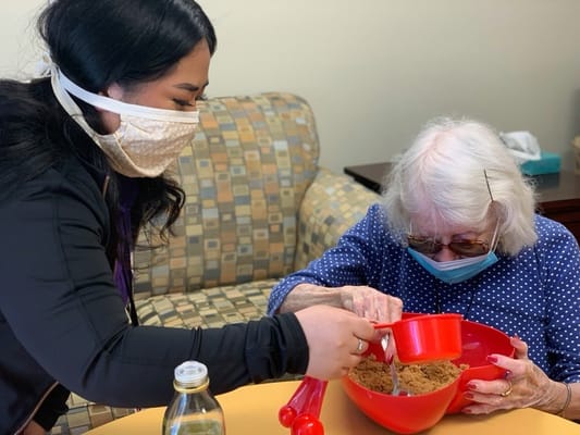Staff assisting a resident with a baking activity