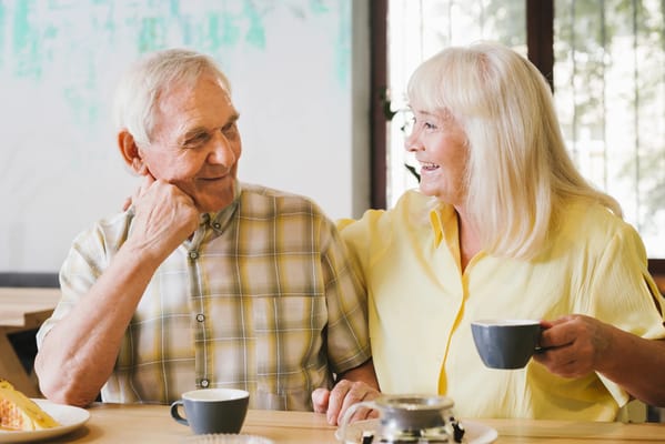 Two seniors enjoying coffee and dessert at a table