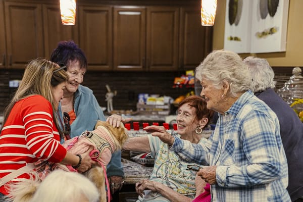 Residents interacting with a pet therapy dog in a common area