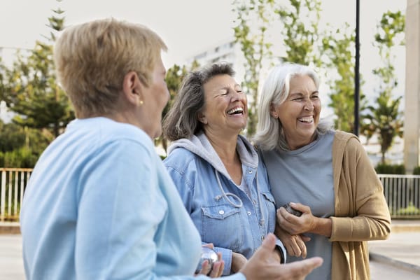 Three smiling women enjoying a sunny outdoor space