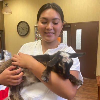 Resident holding a small goat in a common area