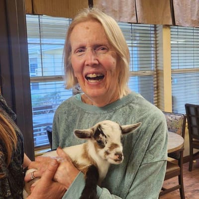 Resident holding a baby goat in a common area