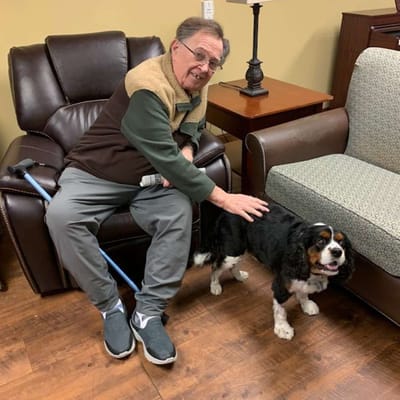 Resident petting a dog in a cozy lounge area