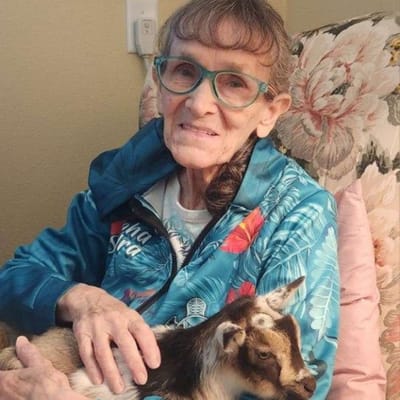 Resident holding a small goat in a cozy chair