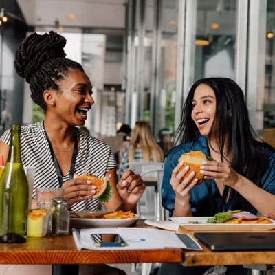 Two women enjoying burgers in a common area