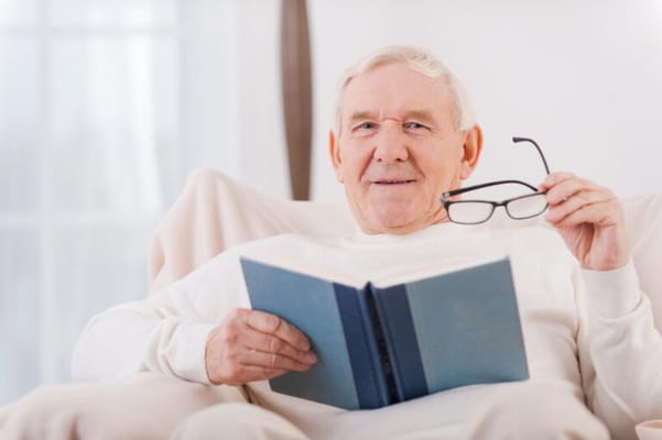 Senior man reading a book in a cozy chair