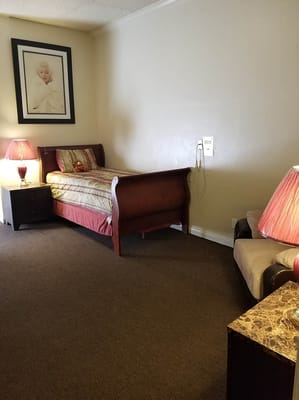 A cozy resident room with a bed and lamp